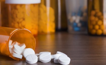 White tables spilled onto a table in front of a medicine container